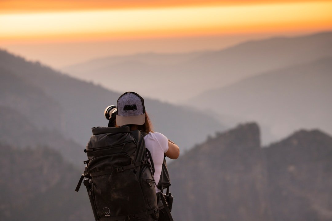 Solo traveler with backpack overlooking scenic mountain landscape at sunrise